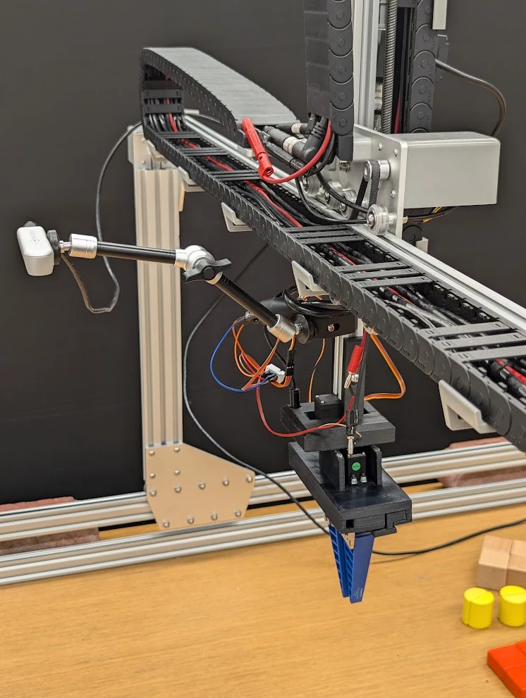 The gantry carriage, camera mount, wiring, and blue gripper.
