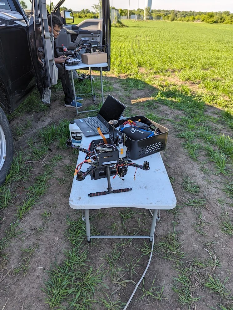 An outdoor drone workstation with flight hardware, a laptop, and support equipment.