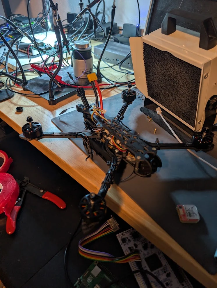 FPV drone assembly on the electronics bench, with the frame and wiring exposed.