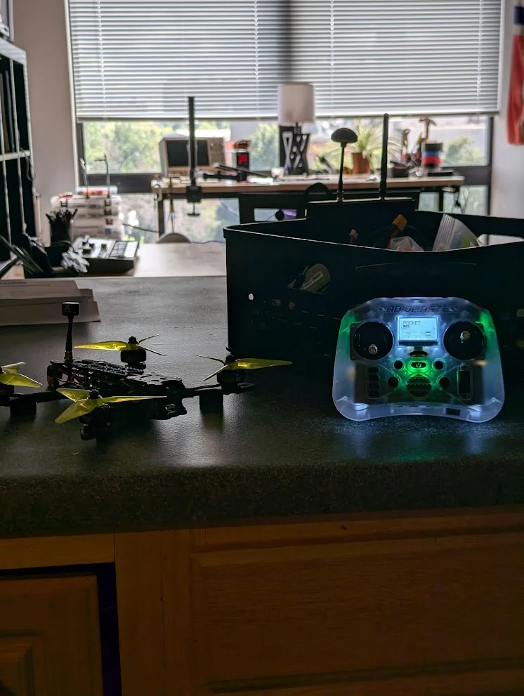 The FPV drone and radio controller together on the workbench.